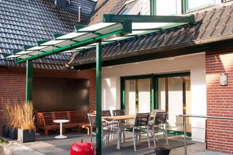 Foto: bestuhlte Terrasse mit grünem Vordach